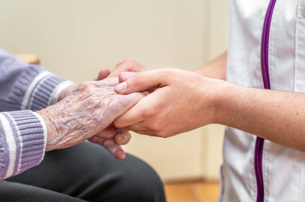 Close-up senior woman hand with her caregiver helping hands holding together, Caregiver visit at home. Home health care and nursing home concept. High quality photo - Fotó, kép
