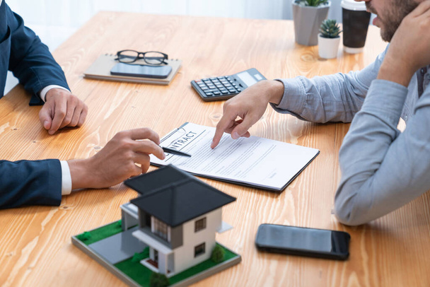 Klient a realitní agent přezkoumávají smlouvu o půjčce, diskutují o termínu, úrokové sazbě a vlastnictví nemovitosti. Před přijetím rozhodnutí proveďte analýzu právního dokumentu a důkladně si přečtěte dohodu. Entita - Fotografie, Obrázek