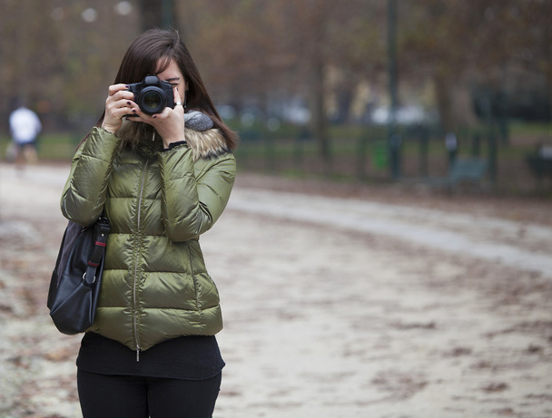 Beautiful girl holding a camera and taking a picture - Valokuva, kuva