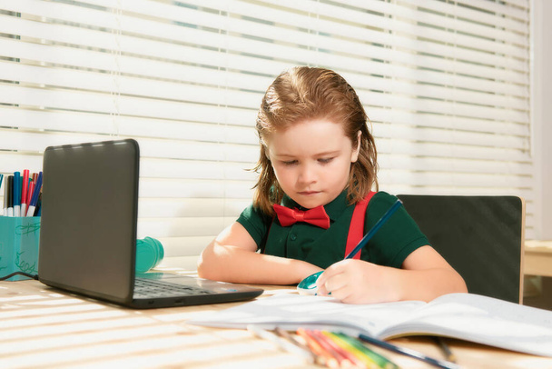Smart school boy does homework in school class. Writes text from laptop notebook - Foto, Imagem