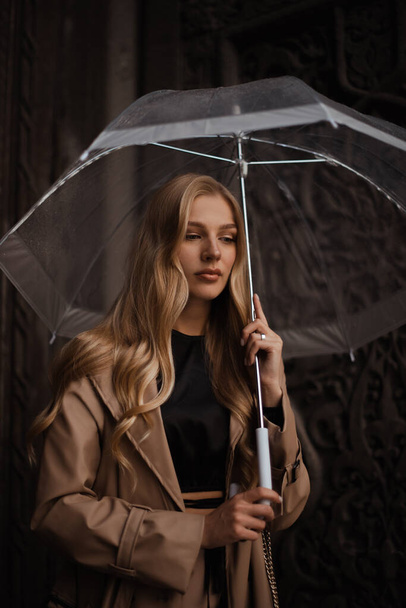 woman holding transparent umbrella. Urban solitude in rain. Woman seeking shelter from rain - Photo, Image