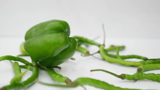 Padající zelená Chilli a Capsicum v bílém pozadí - Záběry, video