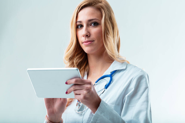Blond medic in copyspace met apparaat, hulpmiddelen telegezondheid, beheert gegevens, verslagen, resultaten, documenten, patiëntenmappen - Foto, afbeelding