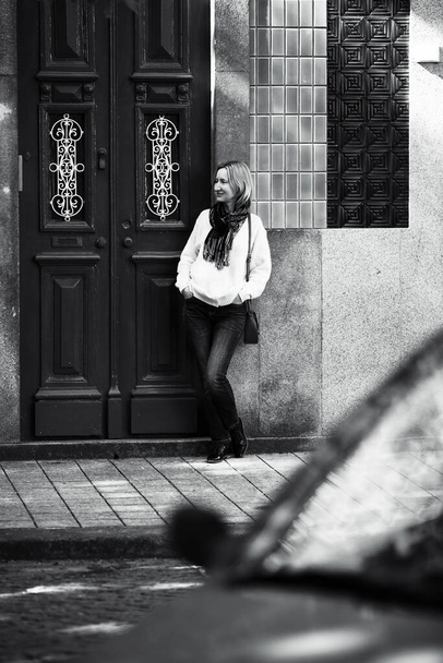Kobieta stojąca przed drzwiami typowego portugalskiego bloku mieszkalnego. Czarno-białe zdjęcie. - Zdjęcie, obraz