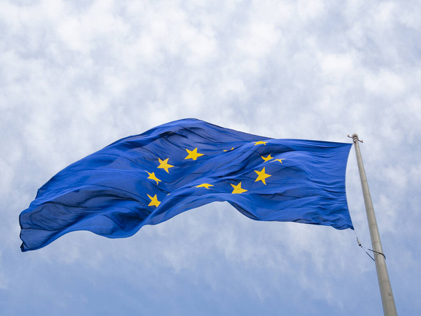 Az Európai Unió zászlója lengett az Európai Parlament épülete előtt. Brüsszel, Belgium, elszigetelve a kék égbolton a naptól - Fotó, kép