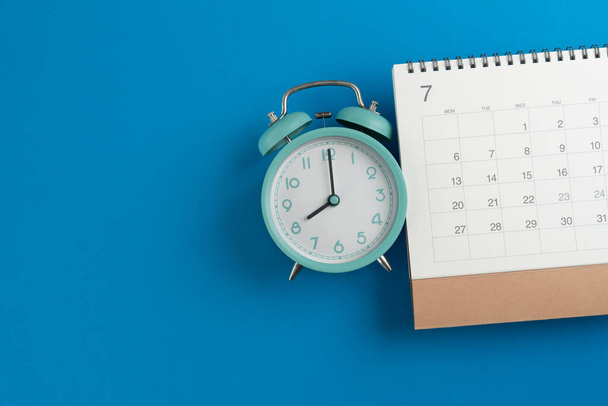 chiusura del calendario e della sveglia sullo sfondo del tavolo blu, pianificazione per riunioni di lavoro o pianificazione del viaggio - Foto, immagini