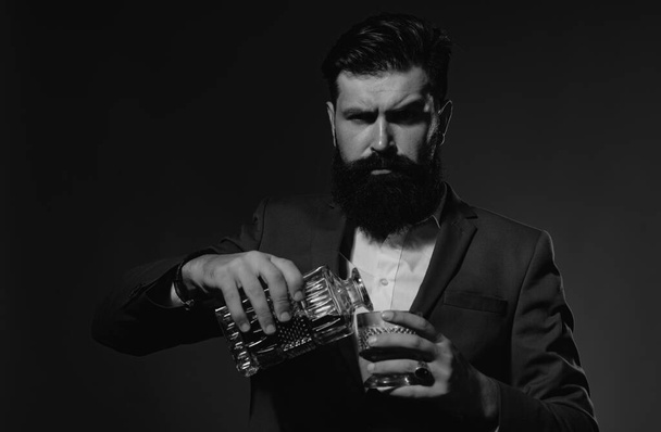Bartender leather apron holding whisky cocktail in glass. Bearded and glass of whiskey - Foto, Imagen