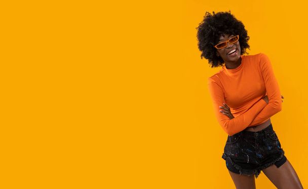 Positive woman with afro hairstyle pointing on yellow background. - Photo, Image