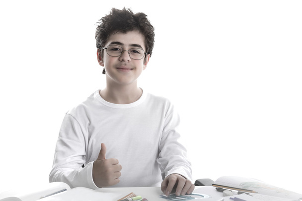 kleiner Junge bei den Hausaufgaben lächelt und zeigt Erfolgsgeste auf bla - Foto, Bild