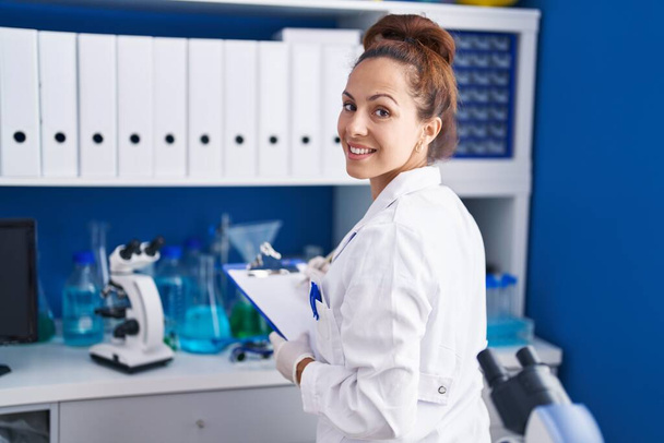 Młoda kobieta naukowiec pisząc na dokument pracy w laboratorium - Zdjęcie, obraz
