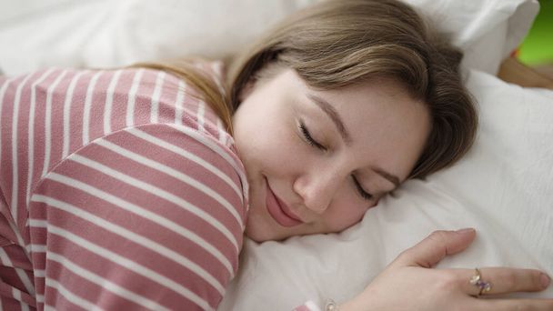 Νεαρή ξανθιά γυναίκα ξαπλωμένη στο κρεβάτι κοιμάται στο υπνοδωμάτιο - Φωτογραφία, εικόνα