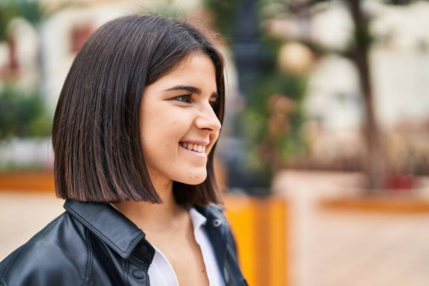 Νεαρή όμορφη ισπανόφωνη γυναίκα χαμογελά με αυτοπεποίθηση κοιτάζοντας προς την πλευρά στο πάρκο - Φωτογραφία, εικόνα
