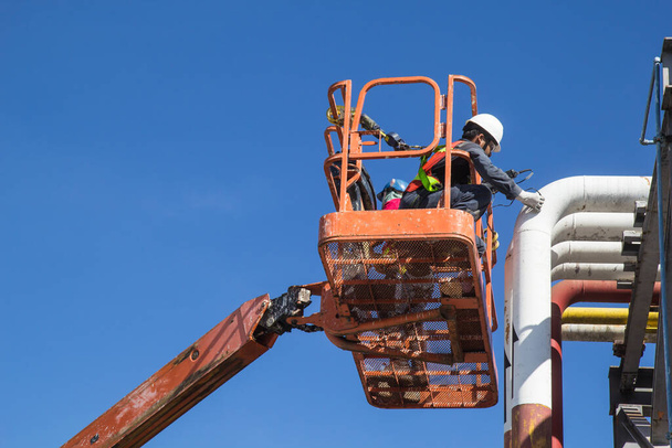 Mannelijke werknemers in een boom lift van de dikte pijpleiding olie inspectie. - Foto, afbeelding
