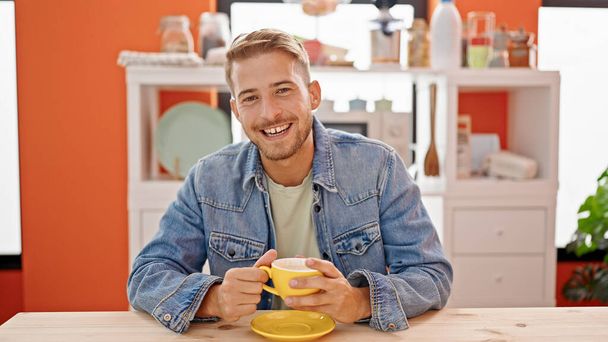 młody biały człowiek pije kawę siedzi na stole mówi w jadalni - Zdjęcie, obraz