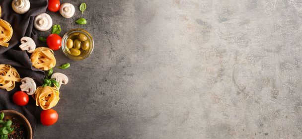 Pasta cruda, funghi, olive e pomodori su fondo grigio con spazio per il testo - Foto, immagini