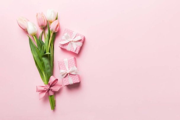 Pink tulips flowers and gift or present box on colored table background. Mothers Day, Birthday, Womens Day, celebration concept. Space for text top view. - Zdjęcie, obraz