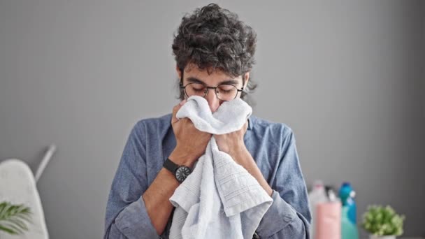 Jonge Spaanse man glimlacht zelfverzekerd ruikende schone handdoek in de wasruimte - Video