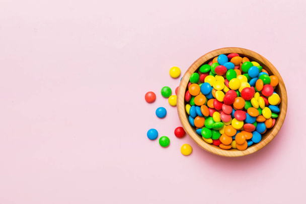 Multicolored candies in a bowl on a colored background. birthday and holiday concept. Top view with copy space. - Foto, afbeelding