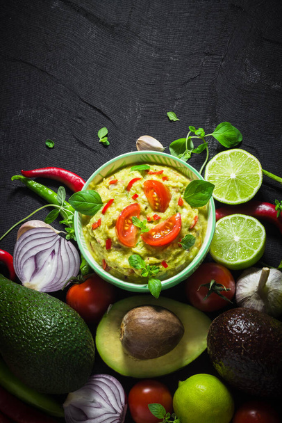 Background with guacamole and ingredients: tomato, chilli pepper, lime, onion, garlic, dill and oregano - Fotó, kép