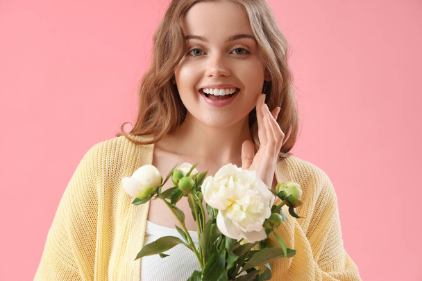 Kaunis nuori nainen kukkakimppu pioni kukkia vaaleanpunainen tausta - Valokuva, kuva
