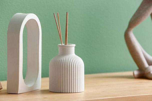 Bottle of reed diffuser and decor on table near color wall in room, closeup - Foto, Imagem
