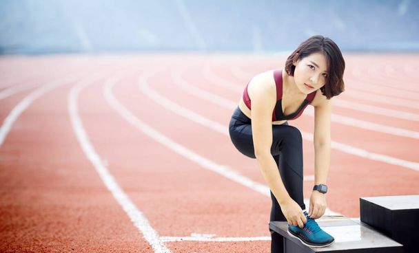 Asian woman tying her shoelaces in preparation for running on the running track. - Foto, Imagem