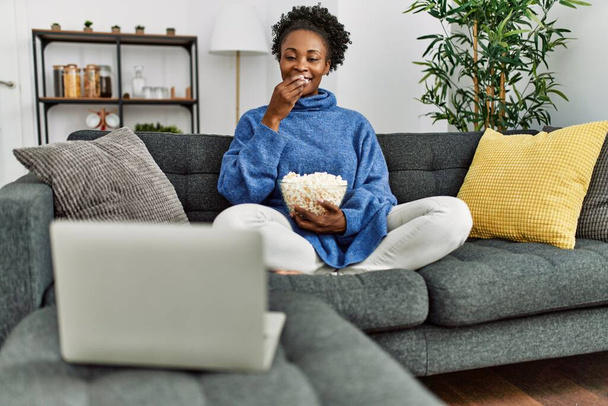 Африканська американка дивиться кіно, сидячи вдома на дивані. - Фото, зображення