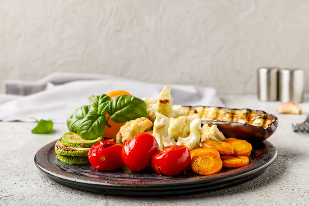 Plate with grilled vegetables and basil on grey background - Foto, Imagen