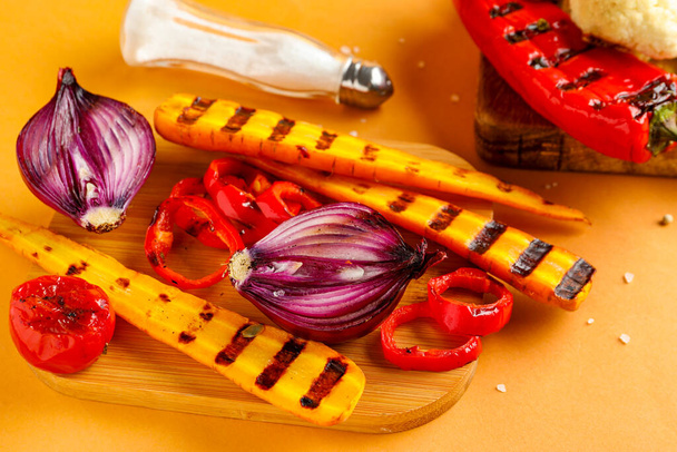 Board with grilled vegetables on orange background - Foto, immagini