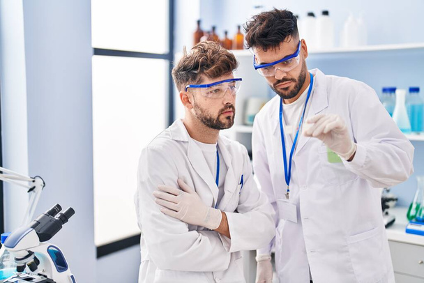 Young couple wearing scientist uniform holding sample at laboratory - Foto, Bild