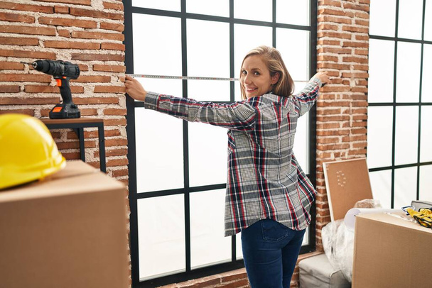 Young blonde woman smiling confident measuring window at new home - Photo, Image