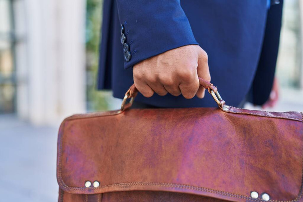 Молодой латинский бизнесмен держит портфель на улице - Фото, изображение