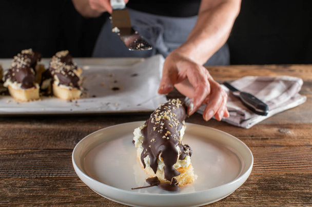 Woman with apron is serving a piece of chocolate covered banana on a plate - Photo, Image