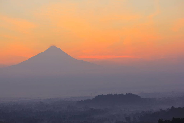 Silhouette du Mont Merapi avec un ciel rouge-orange au lever du soleil. - Photo, image
