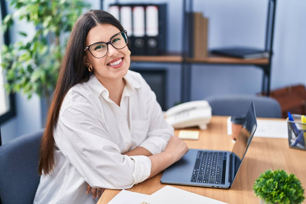 Jonge Spaanse vrouw zakenman met behulp van laptop werken op kantoor - Foto, afbeelding