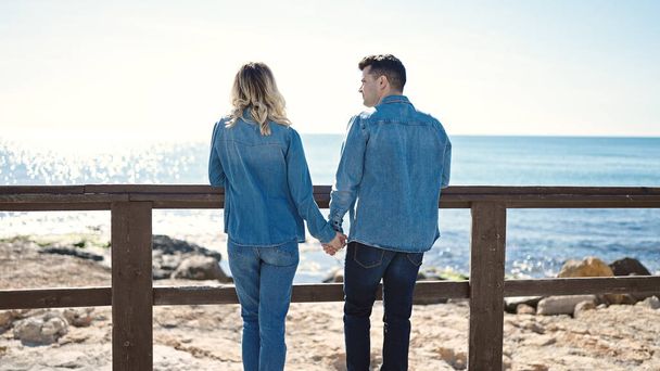男と女のカップルは手を後ろに一緒に海辺で - 写真・画像