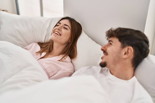 Mand and woman couple smiling confident lying on bed at bedroom - Фото, изображение