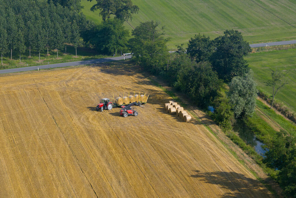 Aerial view of tractor collecting straw bales,Agricultural machine collecting bales of hay,harvest concept, sunny day, Italy - Photo, Image