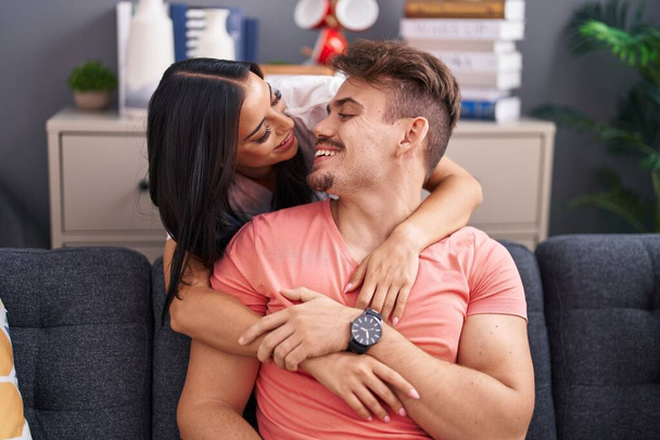 Man and woman couple hugging each other sitting on sofa at home - Foto, Bild