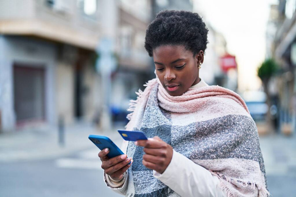 African american woman using smartphone and credit card at street - Фото, изображение