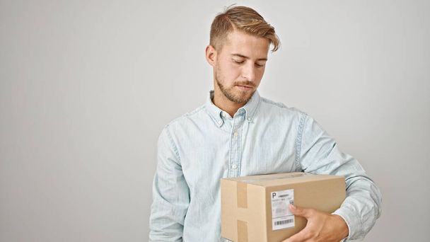 Jeune homme caucasien regardant paquet sur fond blanc isolé - Photo, image
