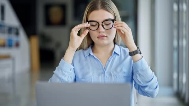 Nuori blondi nainen liiketoiminnan työntekijä käyttää kannettavaa tietokonetta ja kosketuslevy toimistossa - Materiaali, video