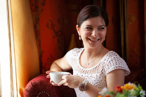 Portrait of a happy young girl in a cafe with a mug in her hand - Foto, afbeelding