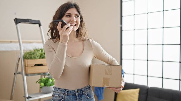 Fiatal gyönyörű spanyol nő hangüzenetet küld okostelefonnal holding csomag az új otthon - Fotó, kép