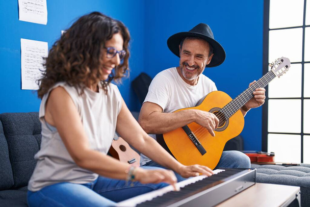 Férfi és női zenészek zongoráznak és klasszikus gitároznak a zenei stúdióban - Fotó, kép