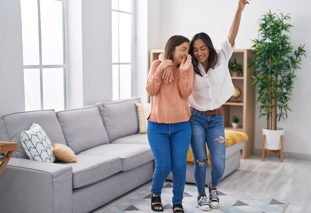 Two women mother and daughter smiling confident dancing together at home - Photo, Image