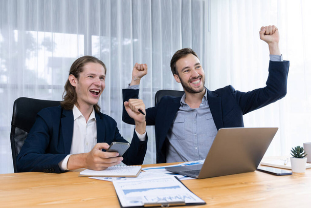 Los hombres de negocios celebran el éxito con expresiones alegres, gesto de puño celebratorio en el cargo después de analizar los datos o alcanzar el objetivo. El trabajo en equipo y la planificación conducen a resultados exitosos. Entidad - Foto, imagen