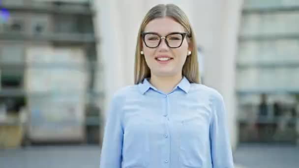 jong blond vrouw zakenman glimlachen zelfverzekerd doen duimen omhoog gebaar op straat - Video