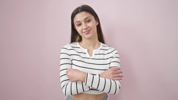 Young beautiful hispanic woman smiling confident standing with arms crossed gesture over isolated pink background - Materiaali, video
