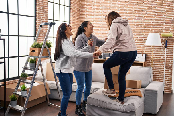 Drei Frauen lächeln selbstbewusst beim gemeinsamen Tanzen im neuen Zuhause - Foto, Bild